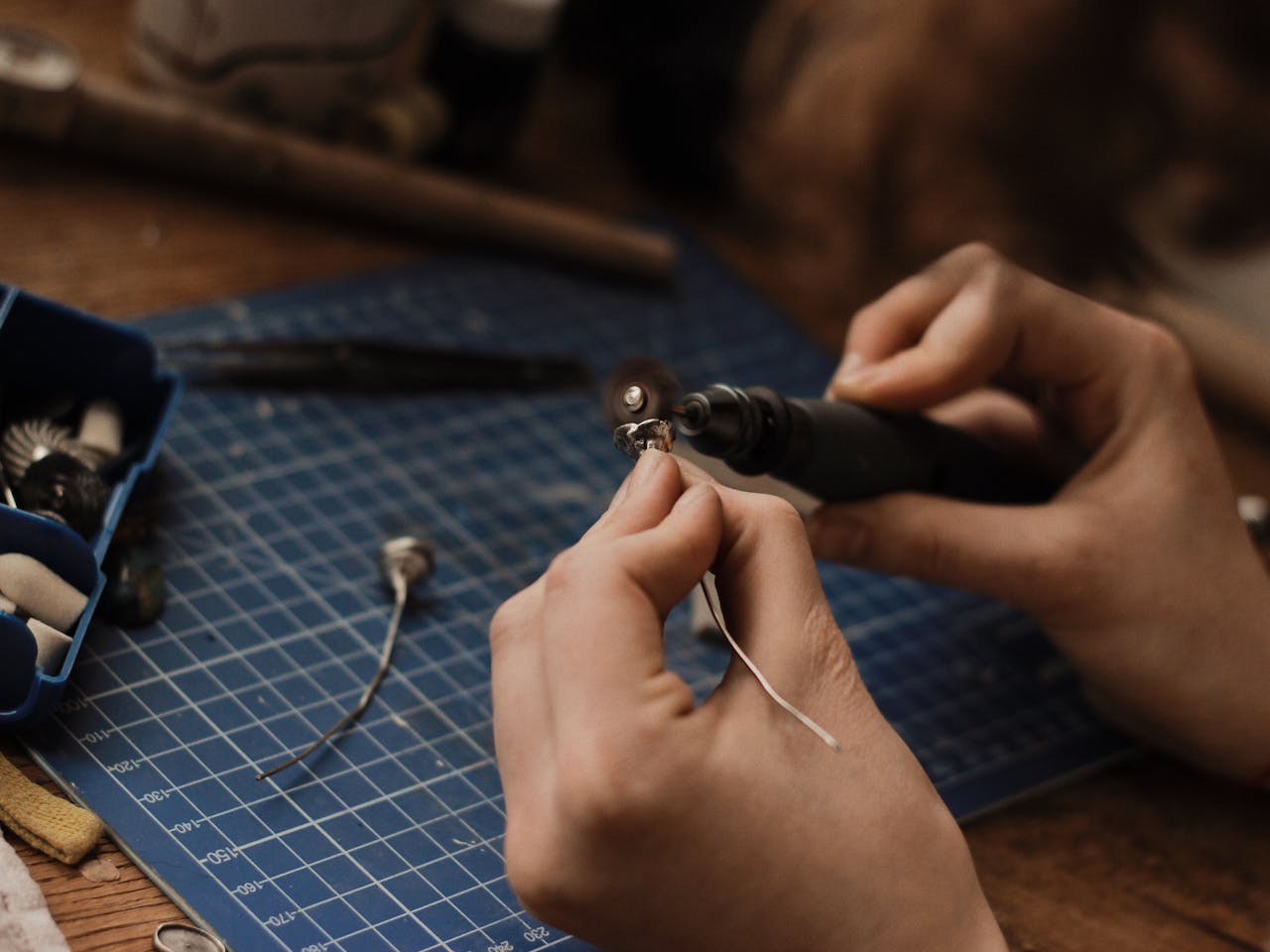 Artisan polishing silver jewelry with precision in a workshop setting.